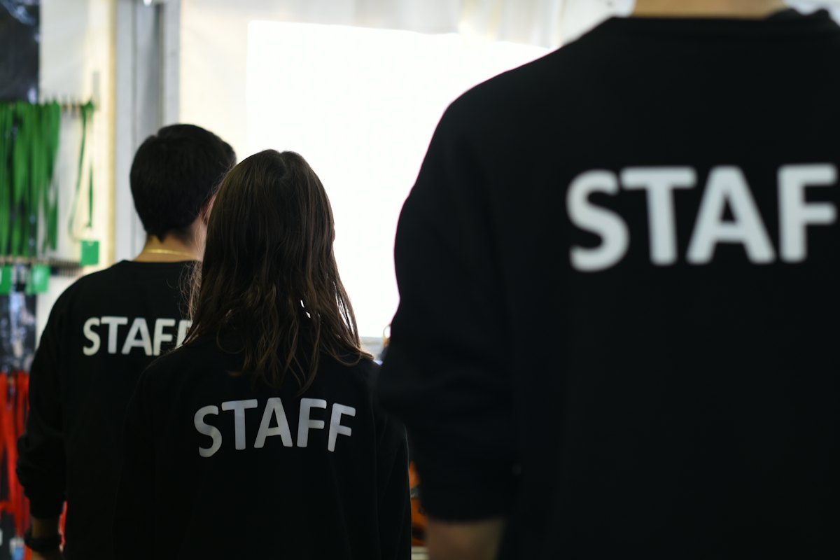 Three event staff wearing black STAFF sweatshirts walking into a venue
